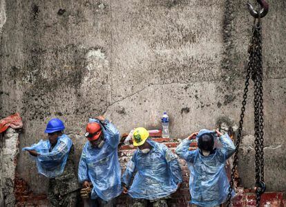 Miembros de los servicios de rescate se ponen chubasqueros antes de seguir con las tareas de búsqueda de supervivientes, en Ciudad de México.