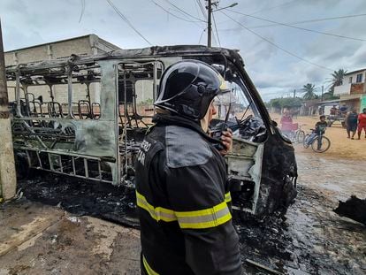 Un bombero este martes en Parnamirim, junto a los restos de un autobús incendiado en la ola de ataques a una veintena de ciudades de Rio Grande do Norte.