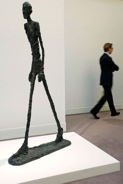 Un hombre pasa ante la escultura <i>L' Homme qui marche I</i>, del artista Alberto Giacometti, previa a su subasta en Londres en enero de 2010.