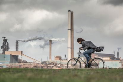 Una ciclista circula cerca de una fábrica de altos hornos en IJmuiden, Países Bajos.