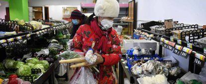  Una mujer compra en una tienda de Pekín, llevando una máscara para evitar el contagio del coronavirus. 
