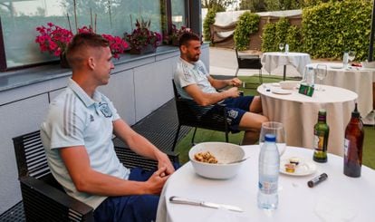 Dani Olmo y Unai Simón siguen a través de un teléfono móvil el amistoso entre España, que juega con el equipo sub 21, y Lituania, este martes en la Ciudad del Fútbol de Las Rozas, en Madrid.