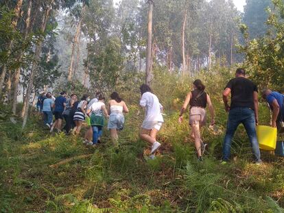 Los vecinos de Moaña (Pontevedra) repelen el fuego a las puertas de sus casas, este domingo por la tarde.