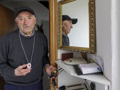 Un anciano muestra el botón de teleasistencia y la conexión de su casa, estropeados.