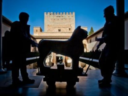 Dos operarios trasladan por el patio de Comares, al fondo la torre, uno de los leones restaurados en 2007.