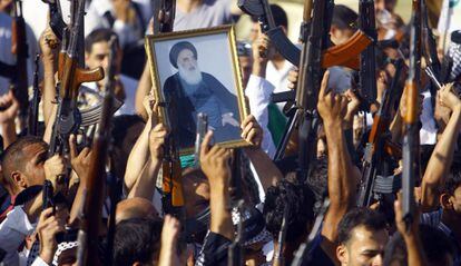 Miembros de tribus iraquíes chiíes alzan fusiles y el retrato del clérigo Ali Sistani, en junio de 2014.