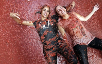 Dos jóvenes participantes en la Tomatina tumbadas en el suelo, en la localidad valenciana de Buñol.