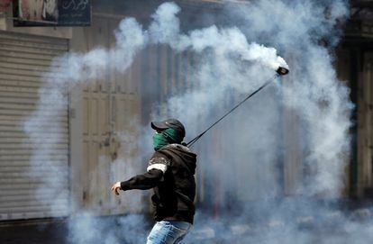 Según fuentes médicas palestinas en la Franja, este sábado al menos tres jóvenes fueron atendidos por herida de bala. En la imagen, un joven lanza un bote de gas lacrimógeno durante un enfrentamiento con las tropas israelíes en Hebrón.