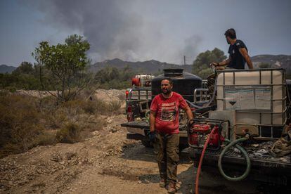 Dos voluntarios trasladan contenedores de agua cerca de los incendios forestales en la localidad de Vati, en la isla de Rodas, este miércoles.  