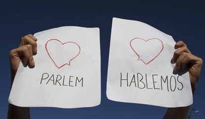Un manifestante sostiene un cartel en el que puede leerse Parlem y Hablemos durante una protesta en Madrid.