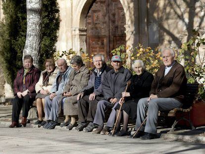 Varios ancianos toman el sol en unos bancos de Olmeda de la Cuesta, Cuenca