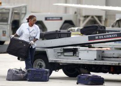 Una trabajadora de handling repartiendo maletas.