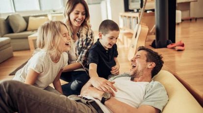 Niños y padres se ríen en el sillón.