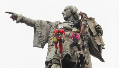 Tres escaladors a l'estàtua de Colom.