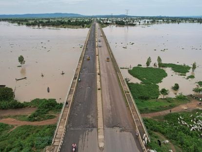 En esta vista aérea tomada el 25 de septiembre de 2022, los residentes locales cruzan el puente Numan mientras conducen hacia un terreno más seguro, lejos de las inundaciones en Numan, estado de Adamawa, al noreste de Nigeria.