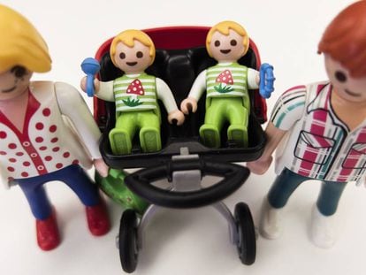 Unos padres múltiples pasean a sus bebés en su carrito gemelar, de Playmobil.