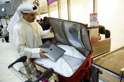 Un hombre guarda su ordenador en su maleta en Kuwait, el pasado marzo