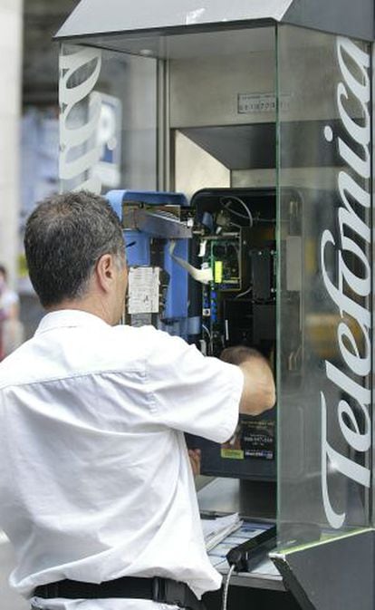 Un empleado de Telefónica repara una cabina de teléfono