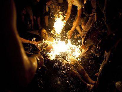 Varias personas intentan apagar las llamas del manifestante que se prendi&oacute; fuego.