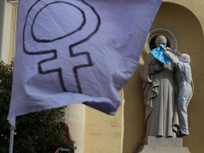 Una activista coloca una soga al cuello de la estatua de  un santo en una iglesia de Sabadell.
