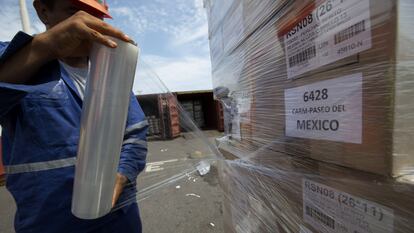 Un trabajador envuelve cajas en plástico antes de cargarlas en un contenedor de envío en el Puerto de Veracruz.