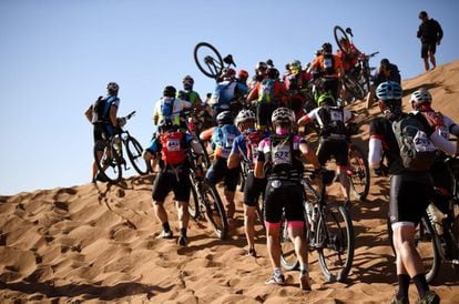 Competidores suben a pie una duna durante la Etapa 4 de la 13ª edición de la carrera de ciclismo de montaña Titan Desert 2018 entre Boumalne Dades y Merzouga, el 2 de mayo de 2018.