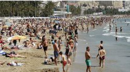 Miles de turistas disfrutan de una soleada jornada en la playa del Postiguet de Alicante, durante el Domingo de Ramos.