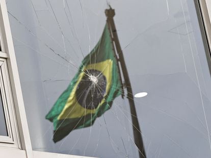 Una bandera de Brasil se refleja en una ventana rota tras el asalto al palacio de Planalto.