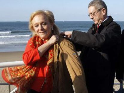 Gallardón ayuda a ponerse el abrigo a la candidata del PP en Asturias, Mercedes Fernández, durante un paseo por el municipio de Salinas.