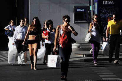 Compradores en una calle madrileña. Pasear y comprar forma parte del ocio que se practica en fin de semana.