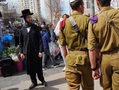 Militares pasan delante de un ultraortodoxo en una calle de Jerusalén este viernes
