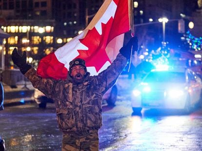 Un hombre camina en la noche del 9 de febrero entre los camiones apostados frente al parlamento de Ottawa, en Canadá, para protestar por la obligatoriedad de presentar un certificado de vacunación para cruzar la frontera de Estados Unidos.