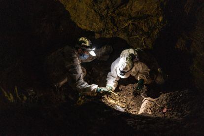 Forensic anthropologists from the Missing Persons Search Unit work part of the night to recover the skeletal remains found in the mass grave.