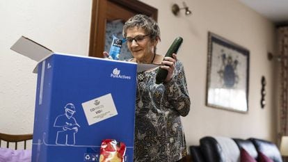 Mª Carmen Clavero, de 84 años, abre el lote de alimentos gratuitos que la iniciativa 'Cestas contra la covid-19' le ha llevado hasta la puerta de su casa.