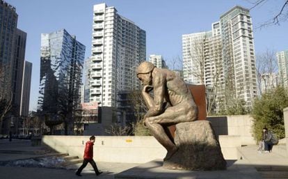 Un hombre pasa frente a una estatua en un distrito de negocios del centro de Pekín.