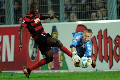 El portero del Leverkusen Bernd Leno intercepta el balón a los pies del jugador Garra Dembele, del Friburgo.