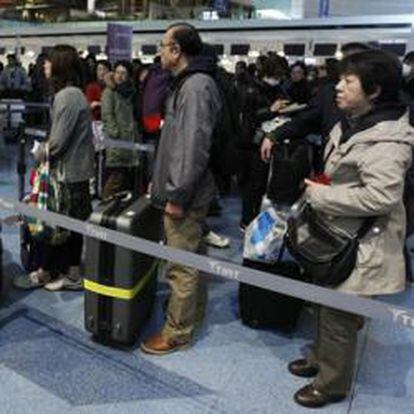 Pasajeros esperan en un fila para comprar los billetes en el aeropuerto de Tokio