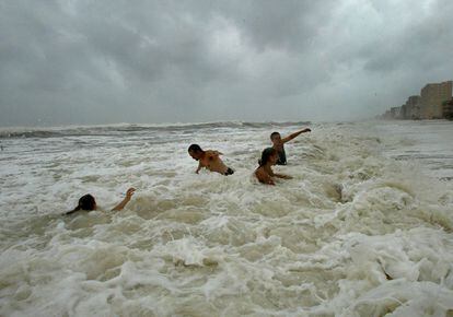 Un grupo de surfista espera la llegada de las olas en Destin, Florida, lejos del centro del huracán Katrina.