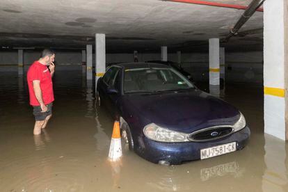 Un hombre observa su coche que ha quedado atrapado en el garaje inundado de su vivienda, tras las fuertes lluvias que han caído en las últimas horas en el barrio de San Ginés de Cartagena (Murcia).