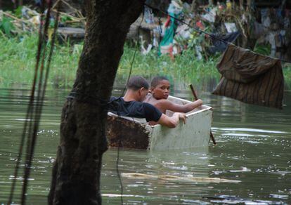 Dos nens utilitzen una caixa de fusta com a pot, en un àrea inundada per les pluges de l'huracà Matthew, al barri de La Puya, a la riba sud del riu Ozama, a Santo Domingo (República Dominicana).