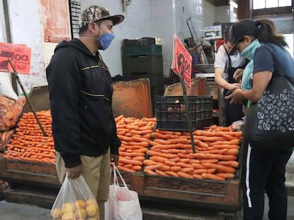 Dos personas con mascarillas compran en el Mercado de la Central de Abasto, en Ciudad de México.