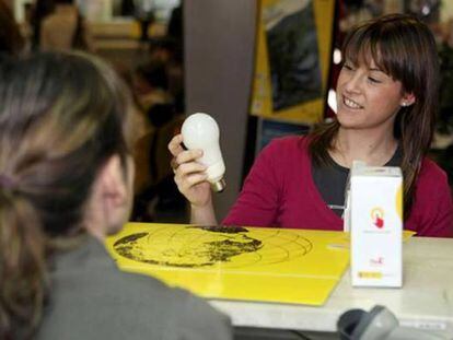 Una joven obtiene una bombilla de bajo consumo en una oficina de Correos de Zaragoza