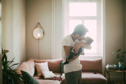 Un padre abraza a su hijo en el salón de su casa. 