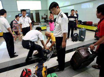 Agentes de aduanas registran el equipaje de un viajero en el aeropuerto de Qingdao, en Pekín.
