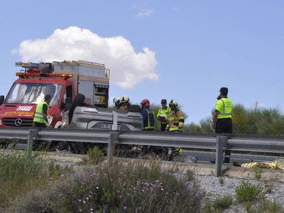 Los bomberos rescatan a una de las víctimas mientras un fallecido permanece sobre el asfalto.