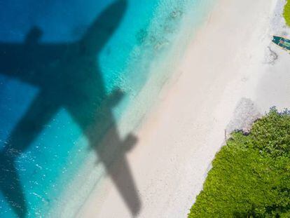Un avión sobrevuela una playa.