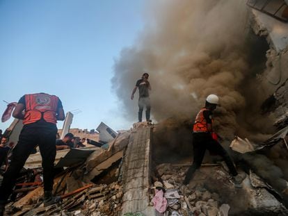 Varias personas buscan supervivientes entre los escombros de un edificio en Jan Yunis, en la franja de Gaza.