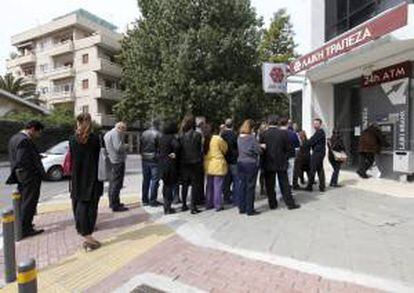 Varias personas hacen cola ante el cajero automático de una sucursal cerrada del Banco de Laiki en Nicosia (Chipre) hoy.