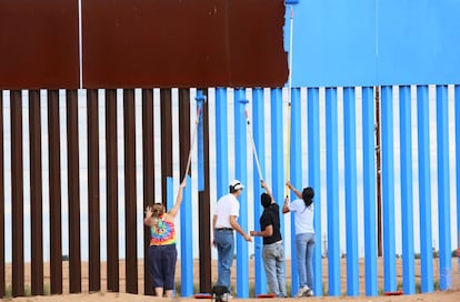 Voluntarios de Erasing the Border pintan la barrera entre EE UU y México para hacerla invisible.