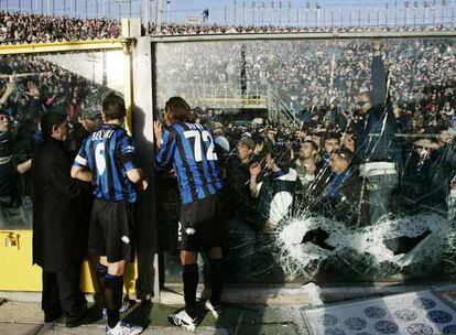 Jugadores del Atalanta tratan de calmar a los violentos, que rompieron las vallas y forzaron la suspensión de su partido con el Milan.